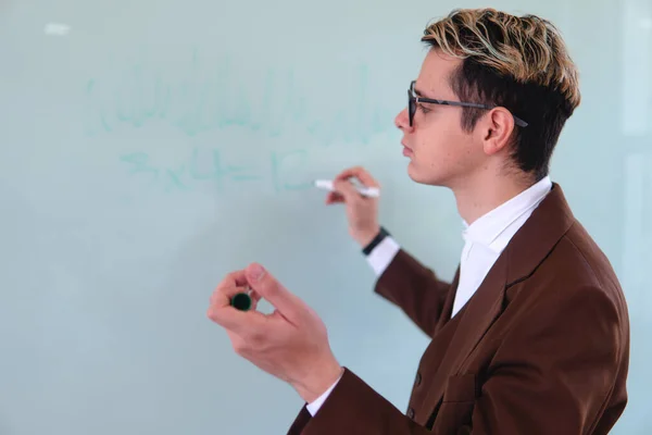 A university professor sketching in the middle of a class on the whiteboard. Elegant man in suit giving a class writing In the whiteboard. High quality photo