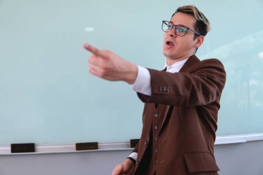 Excited teacher while giving a class. Teacher giving the floor to one of his students. University professor pointing towards his students. High quality photo