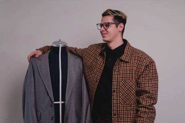Fashion designer in a gray suit. Clothing designer displaying his latest work on a mannequin. Designer in a gray suit make the design. High quality photo