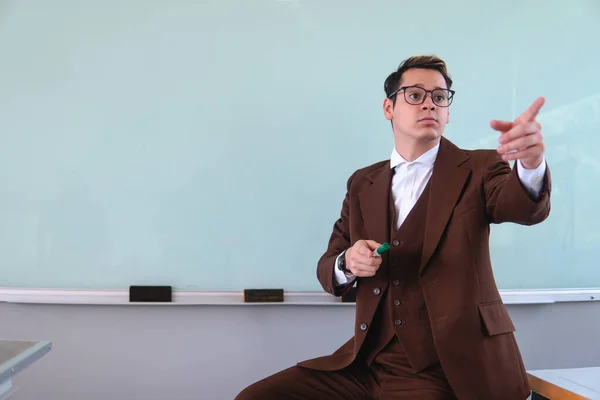 Very smartly dressed college professor pointing to the class. Caucasian and blond man worked in a school giving class. Man dressed as a professor in a university hall. High quality photo