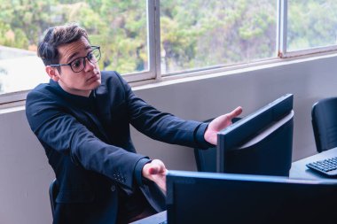 Office worker surprised with what he sees on the computer. Man at his computer raising his arms. Office in front of a window. Caucasian and blond man with computer specialist glasses. High quality