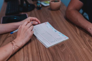 Lawyer filling out a contract with her client. Two people closing a deal at their desk in the office. High quality photo