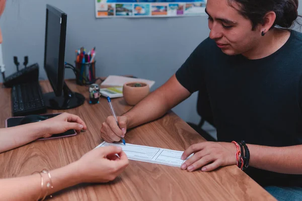 Travel agent closing a deal with a young man. Two people signing a sales contract. Two people at a wooden desk closing a deal. High quality photo