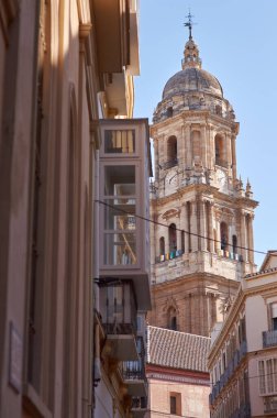 Bir sokaktan katedral kulesi ayrıntıları. Ön planda balkonlar ve mavi gökyüzü