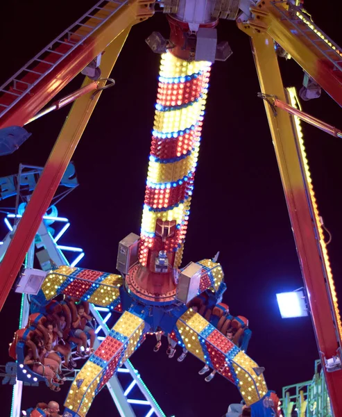 Fairground attraction at night, pendulum in motion.