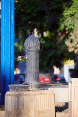 Güneşli bir günde, parkta su içmek için demir çeşme..