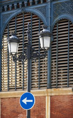 Malaga 'daki Atarazana Pazarı cephesinde gün batımı. Oklu yol tabelası olan dekoratif bir sokak lambası görüntüsü.