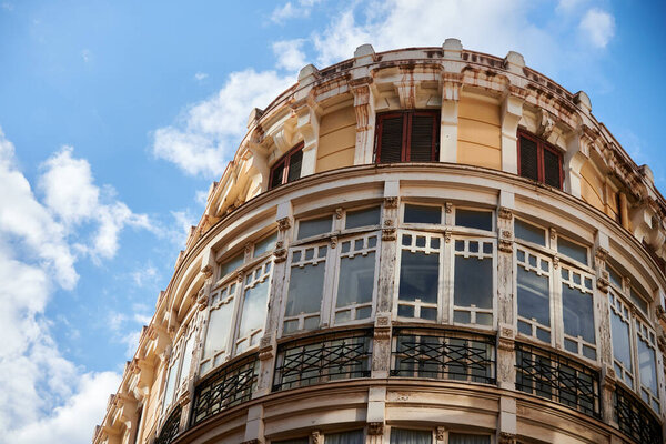 Perspective of a building with a circular corner located in the center of Malaga. Blue sky with clouds at sunset background