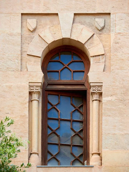 Window with wooden mosaic and Arab horseshoe shape in a wall with stone blocks