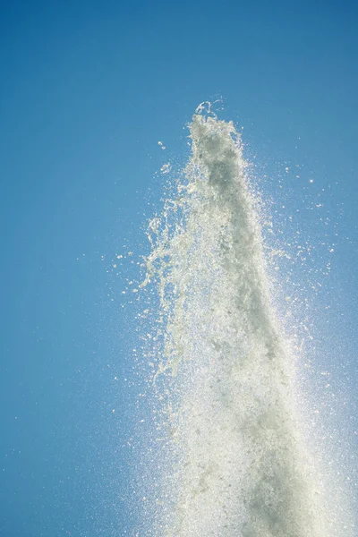 Falling water projected from a fountain. Blue sky to highlight scattered water particles falling downward.