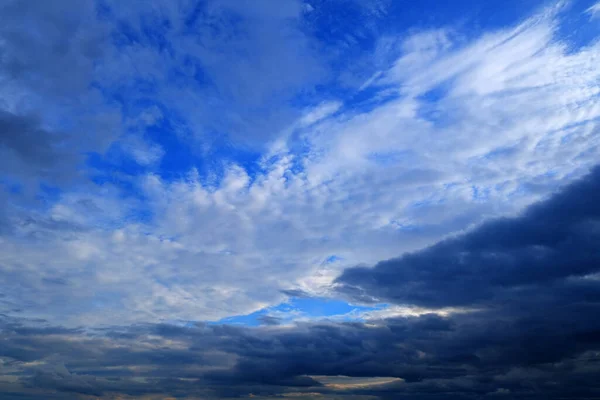 Air clouds in the blue sky, rain storm clouds, blue sky before the rain Nature background. Sunset sun. Warm evening. Sunset. The rays of the sun through the cloud