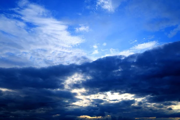 Air clouds in the blue sky, rain storm clouds, blue sky before the rain Nature background. Sunset sun. Warm evening. Sunset. The rays of the sun through the cloud