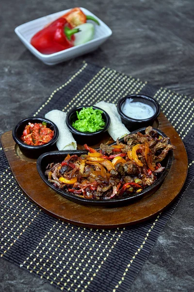 Roast Deer in a cast iron skillet with vegetables and sauces