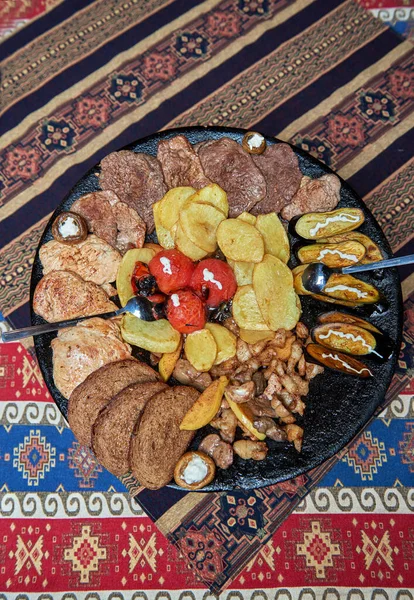 Azerbaijani national food called Sadj vegetables and meat are fried on a large iron pan on fire