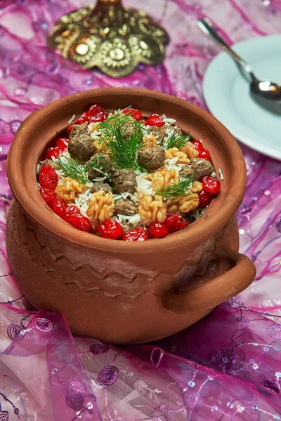 Azerbaijani national pilaf rice cooked in a clay pot with meat and herbs and cherries walnuts studio shot 