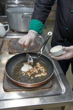 Kaynar tavada kızartılmış mantar ve kremalı profesyonel şef.