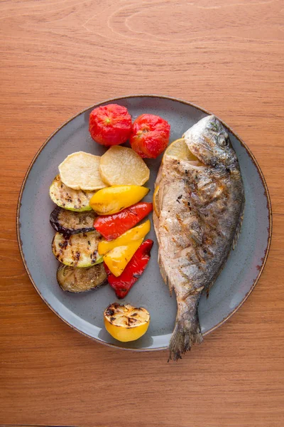 Whole fried fish Dorado with garnish potato pepper tomato lemon