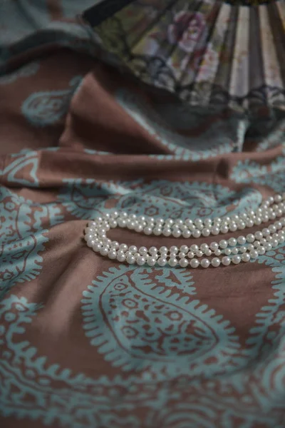 Azerbaijani national national silk scarf called Kelagayi still life with pearls and fan  studio shooting