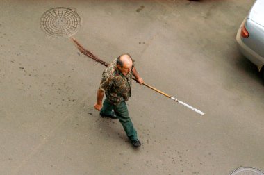 cleaner walking after work with a broom top view of the face is not visible