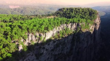 Kanyonun tepesindeki yoğun büyülü orman, devasa muhteşem kayalar, 4k 'de dağların üzerinden uçan destansı insansız hava aracı, yeşil ağaçlı güzel jeolojik mucize, kuş bakışı görüş açısı
