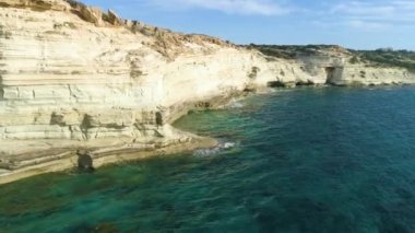 Deniz kıyısının havadan görünen manzarası, dağlı deniz, dik kayalık uçurum, güzel turistik manzara. Turkuaz okyanus insansız hava aracı atışının kıyısındaki beyaz kayalıklar. Su dalgaları kayalara çarpıyor.