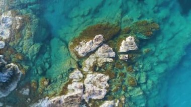 Güneşli bir günde, Turkuaz sularındaki kayalıkların havadan görünüşü. Okyanus dalgaları güzel bir sahil aracının 4K görüntüsü. Yalnız dağ kayasına çarpan deniz, Kıbrıs 'ta turizm beldesi