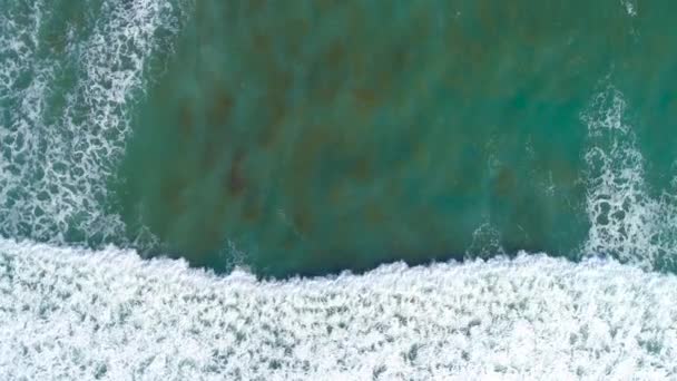 Les vagues océaniques roulent d'en haut. Vue de haut en bas sur drone 4k sur la mer turquoise bleue, vagues cassantes, blanchissement à la chaux. Journée ensoleillée sur la mer. Une énorme houle qui frappe le rivage. Ondes puissantes — Video