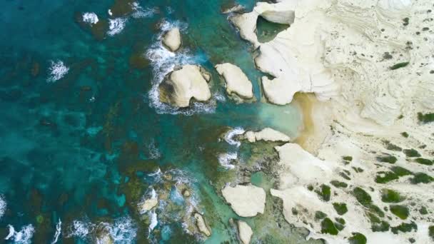 海岸沿いのストリップ、岩の背景を持つビーチに対して海の波がスプラッシュ、海の崖、キプロスの4kトップの空中ビュー — ストック動画