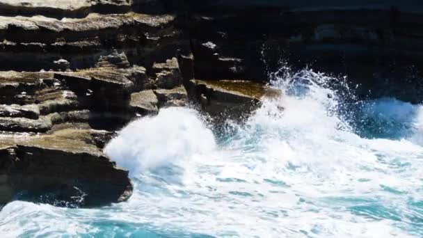 Concepto de tormenta de mar 4k, imágenes del paisaje de agua azul océano y rocas, paisaje marino diurno soleado, devastador y espectacular, las olas del océano se estrellan en las rocas de la costa creando una explosión de agua — Vídeos de Stock