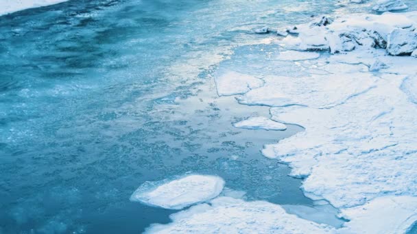 Bevroren rivier, Koude winter of voorjaar landschap, Een bevroren rivier met een enorme stroom, Fragmenten van ijs drijven langs de rivier. Kristalhelder water en ijs, een smeltende gletsjerrivier in IJsland — Stockvideo