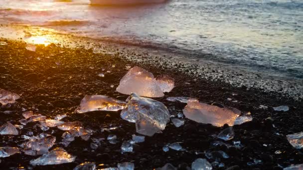 Diamond strand Izlandon, jégdarabok fekete homokon napkeltekor, kristálytiszta víz és egy csodálatos természeti csoda, globális felmelegedés és éghajlatváltozás koncepció, jéghegyek Jokulsarlon gleccserlagúnában — Stock videók
