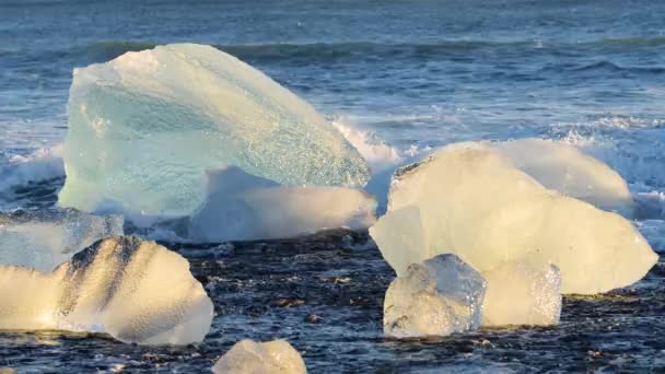 Diamantenstrand in Island, Eisbrocken auf schwarzem Sand bei Sonnenaufgang, kristallklares Wasser und ein wunderbares Naturwunder, Klimaschutzkonzept, Eisberge in der Jokulsarlon Gletscherlagune — Stockvideo