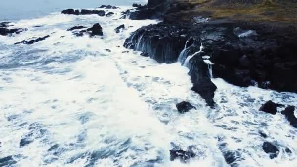 Αεροφωτογραφία των κυμάτων σπάει σε βράχους σε έναν γαλάζιο ωκεανό. Θάλασσα κύματα στην όμορφη παραλία, Πουλιά θέα των κυμάτων του ωκεανού συντρίβεται σε ένα άδειο βράχο βράχο γκρεμό από ψηλά, Ισλανδία — Αρχείο Βίντεο
