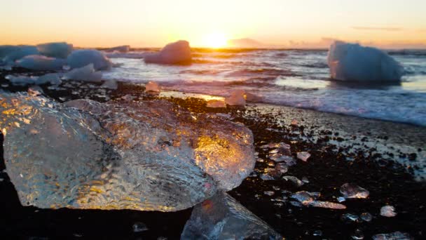 Diamond strand Izlandon, jégdarabok fekete homokon napkeltekor, kristálytiszta víz és egy csodálatos természeti csoda, globális felmelegedés és éghajlatváltozás koncepció, jéghegyek Jokulsarlon gleccserlagúnában — Stock videók