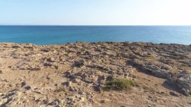 Yeryüzünün kıyısındaki hava manzarası, turkuaz sakin deniz dalgaları kayalık bir uçuruma, okyanus esintisine, saflığa ve dokunulmamış doğaya, jeolojik harikaya, Kıbrıs 'a çarpıyor