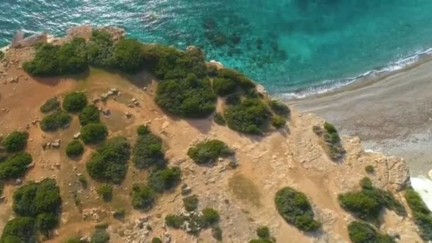 鳥の目のビューから海の海岸線、青い海の波は、美しいビーチの空中ビュードローン4kショット、クリアターコイズブルーの水と白い岩の岩の上に岩の海岸を洗う。キプロス — ストック動画