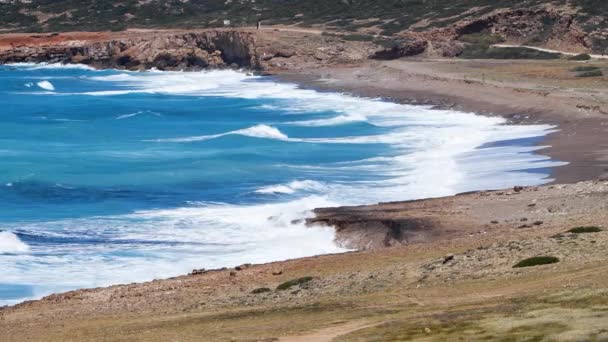 海の風景映像青い水と岩、晴れた日の海の風景、破壊的で壮大な、海の波が海岸の岩の上に衝突し、水の爆発を作り出します — ストック動画
