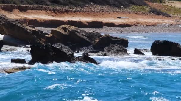 Πλάνα τοπίων με καταγάλανα νερά και βράχους, Ηλιόλουστο τοπίο ημέρας, καταστροφικό και θεαματικό, κύματα ωκεανού συντρίβονται στα βράχια της ακτής δημιουργώντας μια έκρηξη νερού — Αρχείο Βίντεο