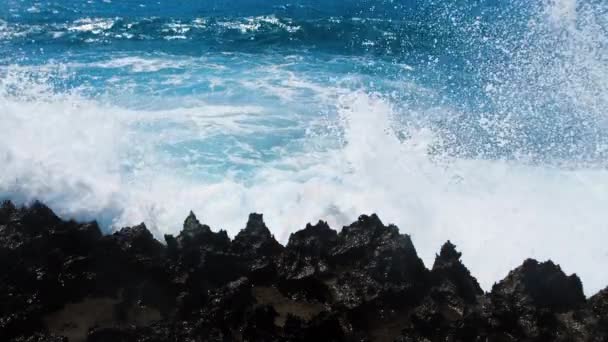 Морские волны разбиваются на скалах побережья, создавая взрыв воды, концепцию морской бури 4k, пейзажные кадры океанической голубой воды и скал — стоковое видео