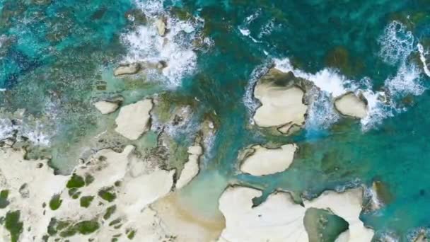 Légi felvétel hullámok törnek sziklák a kék óceánban. Tengeri hullámok a gyönyörű strandon, Madarak szeme láttára óceán hullámok összeomlik egy üres kő szikla sziklák felülről — Stock videók