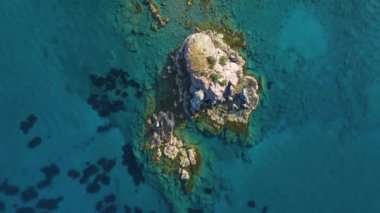 Güneşli bir günde, Turkuaz sularındaki kayalıkların havadan görünüşü. Güzel kıyılarda okyanus dalgaları. Yalnız dağ kayasına çarpan deniz, Kıbrıs 'ta turizm beldesi