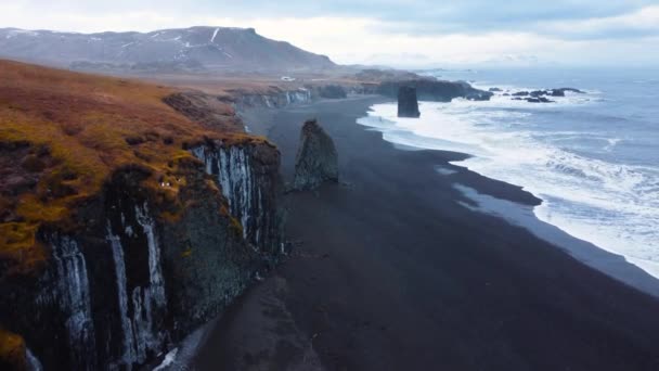 Olas marinas en hermosa playa de arena negra, Ojo de pájaro Vista aérea de las olas del océano estrellándose contra un acantilado de piedra vacío, Paisaje volcánico en Islandia — Vídeo de stock