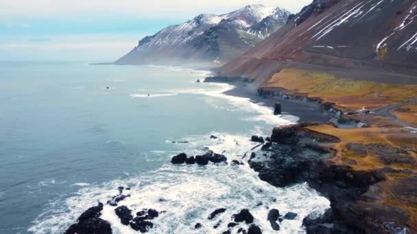 푸른 바다에서 파도가 바위에 부딪치는 장면 이 공중에서 눈에 띈다. 아름다운 해변에 밀려오는 바 다 파도, 위에서 내려다 보이는 텅 빈 산 절벽 과 충돌하는 바 다 파도가눈에 들어옵니다, 아이슬란드 — 비디오