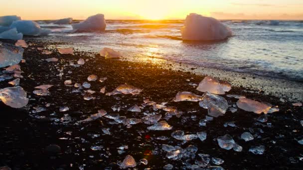 Diamentowa plaża na Islandii, Kawałki lodu na czarnym piasku o wschodzie słońca, krystalicznie czysta woda i cudowny cud natury, koncepcja globalnego ocieplenia i zmiany klimatu, góry lodowe w lagunie Jokulsarlon — Wideo stockowe