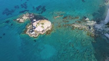 Ada ve Mavi Deniz kuş bakışı. Keskin bir uçurum. Turkuaz suyu olan kayalık resif, güzel sahil manzaralı deniz dalgaları 4k dronu, turizm merkezi, tatil yeri, Kıbrıs Rum Kesimi