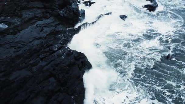 Fale rozbijają się na czarnych skałach wulkanicznych w błękitnym oceanie, Burza na morzu Widok z powietrza, Islandia — Wideo stockowe