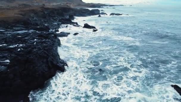 Costa del océano en Islandia, olas rompen en las rocas, El mar erosiona las rocas volcánicas, Vista aérea — Vídeo de stock