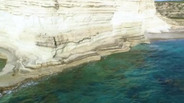 Deniz kıyısının havadan görünen manzarası, dağlı deniz, dik kayalık uçurum, güzel turistik manzara. Turkuaz okyanus insansız hava aracı atışının kıyısındaki beyaz kayalıklar. Su dalgaları kayalara çarpıyor.