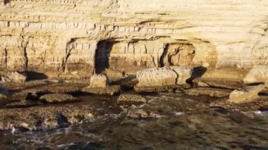 Kayalık Kıyı Hattı üzerinde Mavi Akdeniz ile birlikte Uçan Okyanus Suyu Gün Batımında Güneş 'e Doğru. Kuş Gözü Görünümü 4K Sinematik İnsansız Hava Aracı. Deniz kıyısının üzerinde Gökyüzünden, Kıbrıs