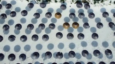 Tatiller, deniz kıyısında tatiller, kumlu sahilde şemsiye manzarası, güneşli hava. Tropikal bir yaz mevsiminde palmiye ağaçları, şemsiyeler, kum ve okyanus mavisi suyla